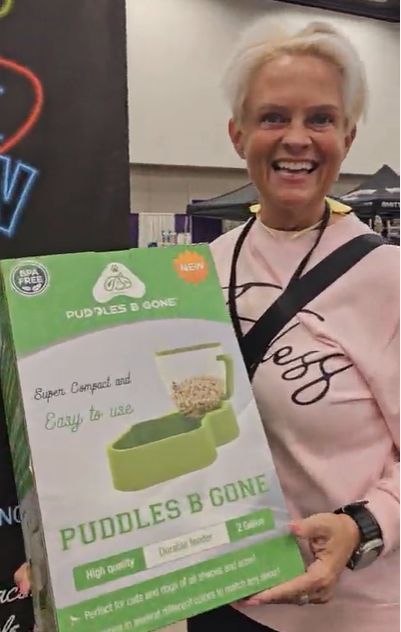 A happy attendee holding a Puddles B Gone cat water fountain
