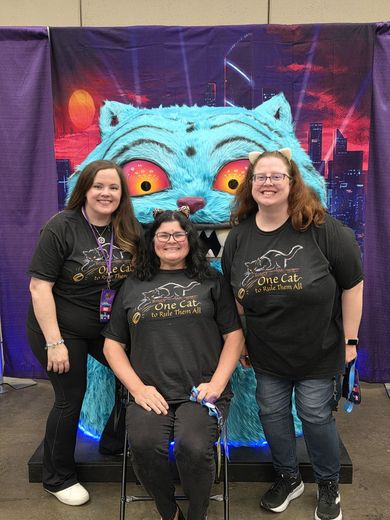 Three friends in matching One Cat shirts at the giant cat photo op