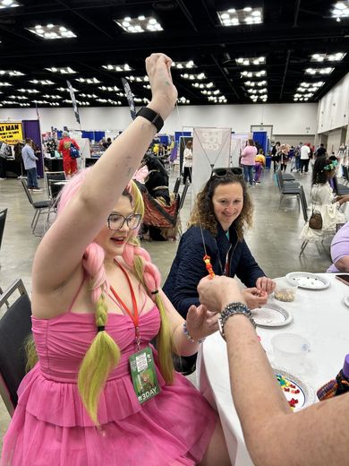 Cosplayer in pink raising her hand during a PurrCon activity