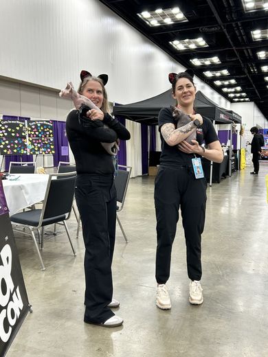 Two attendees in cat ears holding kittens at PurrCon