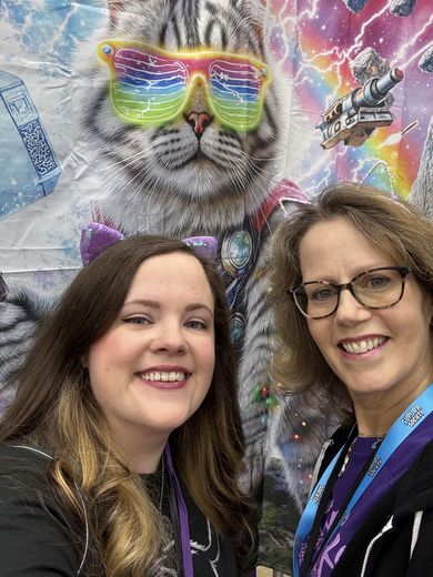Two friends taking a selfie in front of a cosmic cat mural