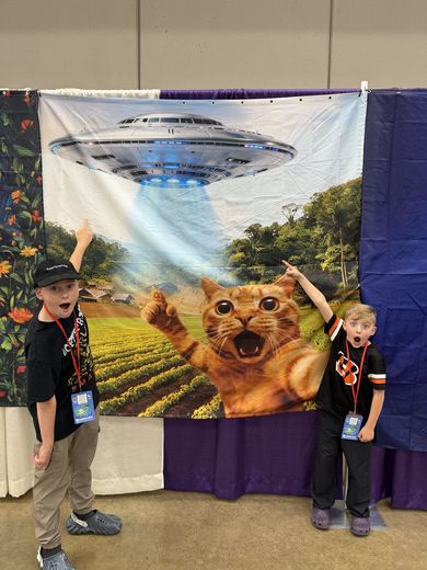 Two kids pointing at a UFO cat photo backdrop