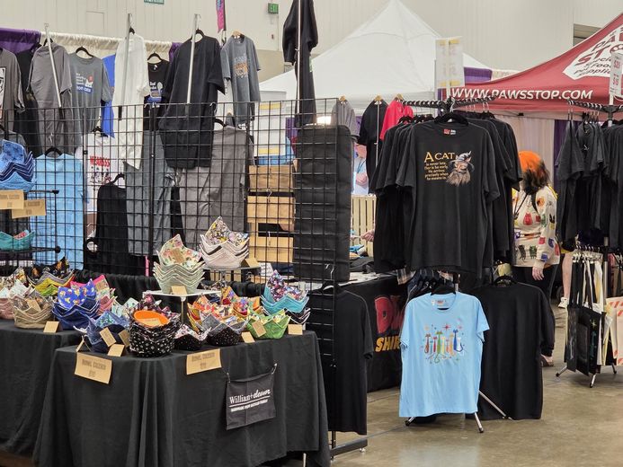 Cat-themed T-shirts and gifts at a PurrCon vendor booth