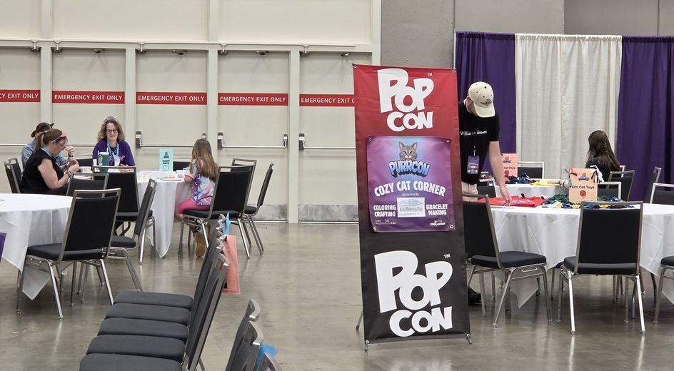 PopCon Cozy Cat Corner sign beside the PurrCon activity tables