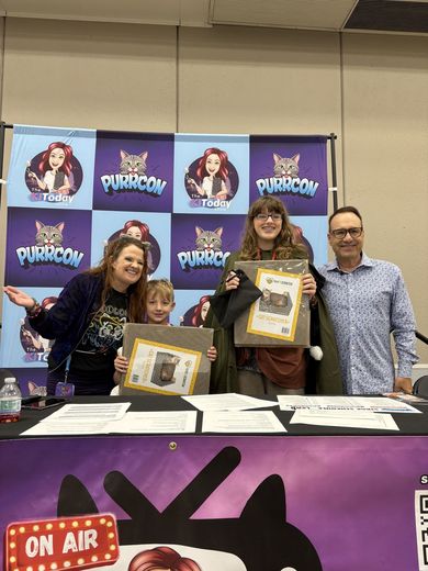 Family holding framed art at The Cat Conversation stage