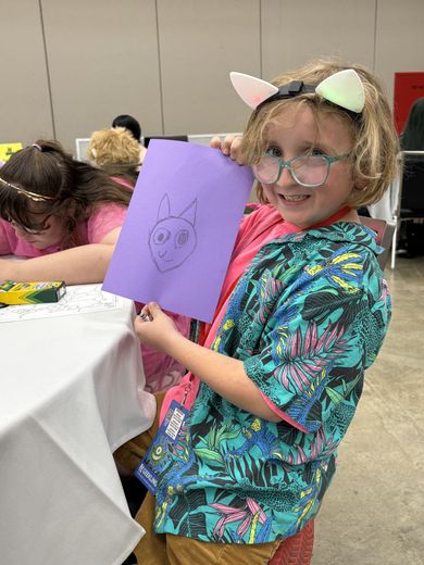 Child in cat ears showing off a cat drawing