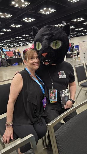Attendee posing with a giant black cat mascot