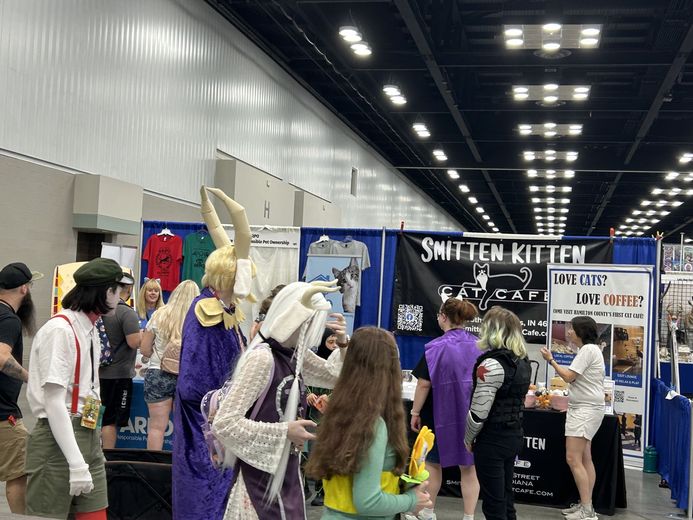 Cosplayers walking past the Smitten Kitten Cat Cafe booth