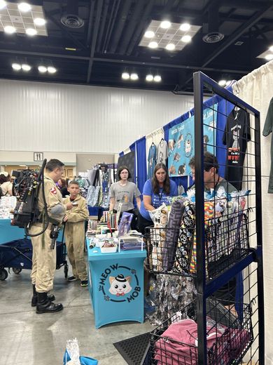 Vendor booths and cosplayers along a PurrCon aisle