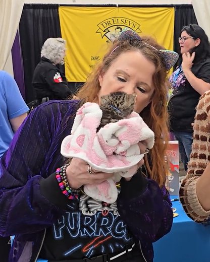 Attendee kissing a kitten at the Dr. Elsey's booth
