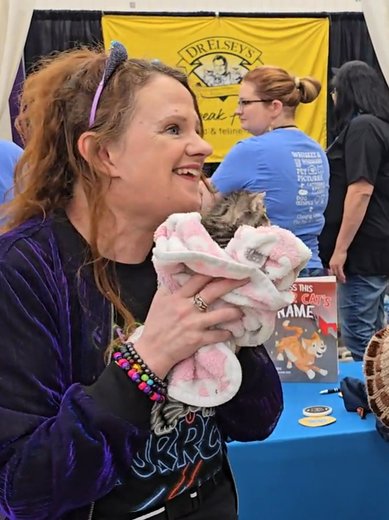Attendee smiling with a kitten at the Dr. Elsey's booth